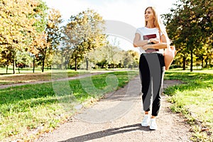 Beautiful schoolgirl walking in the Park holding a book in a goo