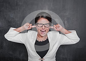 Beautiful screaming woman with fingers in her ears on the blackboard