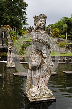 Beautiful sculpture of deity warrior or demon of balinese mythology in majestic park Tirta Gangga on Bali, vertical. Old monument