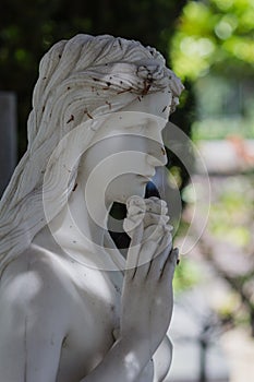 Beautiful sculpture of a sorrowful young woman in a gerden