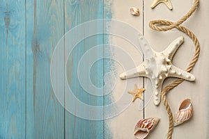 Beautiful sea stars, shells, rope and sand on blue wooden background, flat lay. Space for text