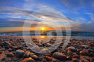 Beautiful sea sunset and sun glare on wet pebbles