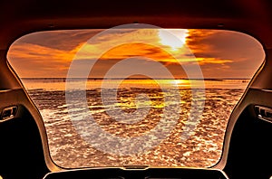 Beautiful sea view from inside car trunk. Sea view with orange sky and clouds in sunset time at the beach. Freedom summer travel