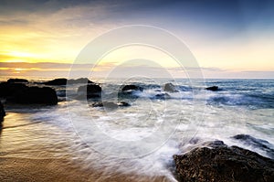 beautiful sea view scenery over stunning sunrise background.sunlight beam and soft wave hitting beach rocks