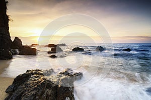 beautiful sea view scenery over stunning sunrise background.sunlight beam and soft wave hitting beach rocks