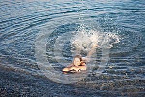 The happy girl in the sea swims and squirts with her feet photo