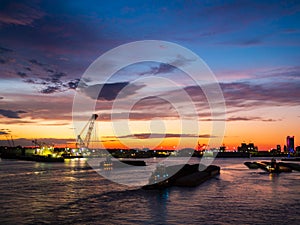 Beautiful seaport city at sunset, orange and yellow silhouette of the port cranes