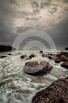 Beautiful seascape for background. Beach with rocks and stones. Low tide. Motion water. Cloudy sky. Slow shutter speed. Soft focus