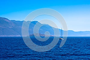 Beautiful seascape with calm blue Mediterranian sea, mountains in mist and boat, touristic season photo
