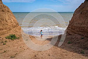 Beautiful seascape. The girl in a dress and a white hat goes down to the sea