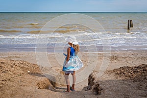 Beautiful seascape. The girl in a dress and a white hat goes down to the sea