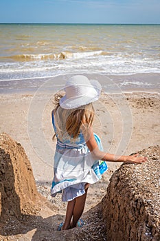 Beautiful seascape. The girl in a dress and a white hat goes down to the sea