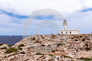 Beautiful seascape with a lighthouse Faro de Cavalleria on a cliff and a cruise ship in the sea. Menorca, Balearic islands,