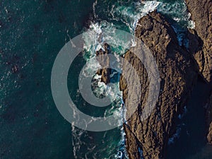 Beautiful seascape. Majestic ocean and dark brown stones. White waves. A clear day. Clear transparent water. No people. High angle