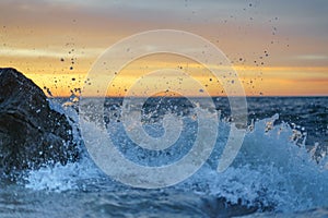 Beautiful seascape of an ocean with rolling waves crashing against a rocky shoreline at sunset