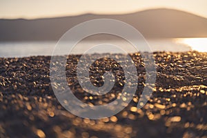 Beautiful seascape, pebble beach in the glare of the sun at sunset. Summer vacation background