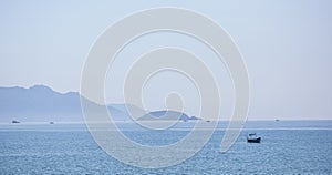 A beautiful seascape, a sailboat floating in the distance amidst majestic mountains.