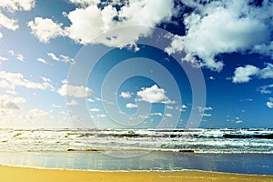 Beautiful seascape with sea waves, blue sky, white cumulus clouds and sand beach. Summer vacation tropical landscape.