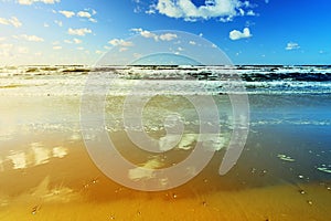 Beautiful seascape with sea waves, blue sky, white cumulus clouds and sand beach. Summer vacation tropical landscape.