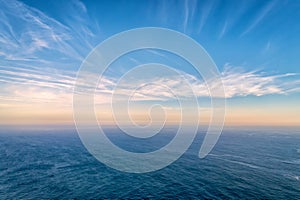 Beautiful seascape at sundown, clouds and calm sea waves, clear blue sky