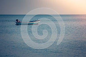 Beautiful seascape view of fishing boat floating on the sea with sunset light in the background.