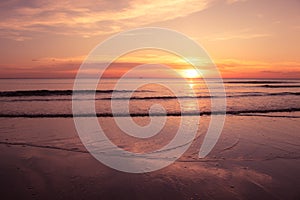 Beautiful seascape view in twilight time with sea wave and orange sunset in background.