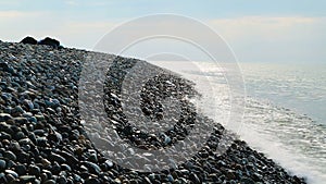 Beautiful seascape with warm waves splashing against sunlit pebble beach, relax