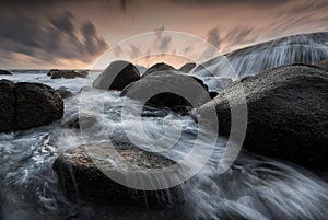 Beautiful seascape with wave and rock at sunset