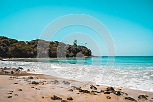 Beautiful secluded beach on an isolated island. Blue water and white waves spume on a sandy beach with stones in Sri Lanka. Escape