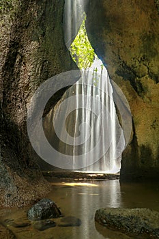 Beautiful secret Tukad Cepung Waterfall in Bali, Indonesia. Long exposure shot. Rays of sun are shining through the mountain over