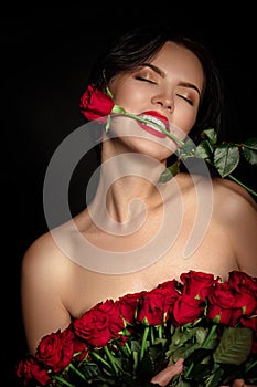 Beautiful young woman with a large bouquet of red roses