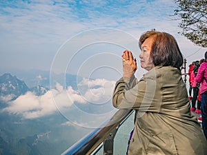 Beautiful Senior asian women stand on Tianmen mountain Glass balcony with winning Pose and beautfiul View on the mountain photo