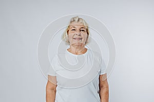 Beautiful senior blonde woman smiling and looking at camera over white background. Human emotions, facial expression