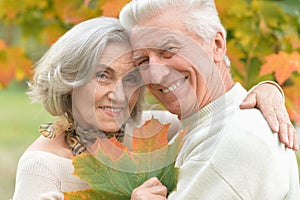 Beautiful senior couple in autumn park with leaves