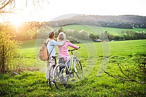 Beautiful senior couple with bicycles outside in spring nature.