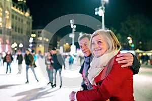 Beautiful senior couple ice skating in city centre. Winter