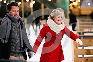 Beautiful senior couple ice skating in city centre. Winter