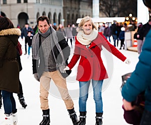 Beautiful senior couple ice skating in city centre. Winter