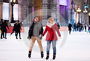 Beautiful senior couple ice skating in city centre. Winter