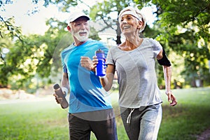 Beautiful senior couple running outside in forest