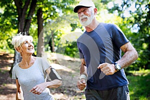 Beautiful senior couple running outside in forest