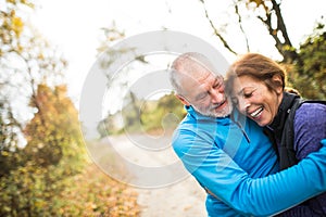 Beautiful senior couple running outside in sunny autumn forest