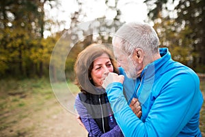 Beautiful senior couple running outside in sunny autumn forest