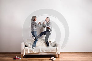 Beautiful senior couple standing on couch, dancing. Studio shot.