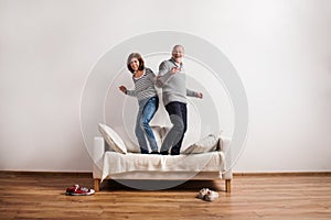 Beautiful senior couple standing on couch, dancing. Studio shot.