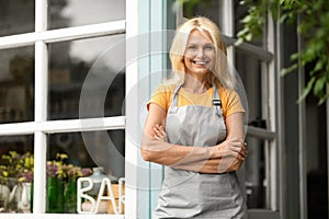 Beautiful Senior Female Wearing Apron Standing On Terrace At Countryside Bar