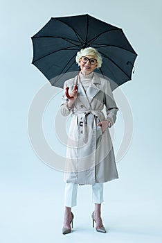 beautiful senior lady in autumn outfit holding umbrella,