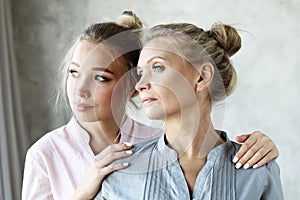 Beautiful senior mom and her adult daughter are hugging, looking at camera and smiling. At Home