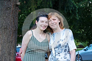 Beautiful senior mother and her adult daughter look at the camera and smile