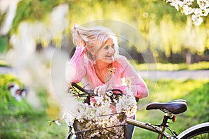 Beautiful senior woman with bicycle outside in spring nature.